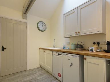 A kitchen area with cupboards sink dishwasher and kettle at The Snug in Embleton