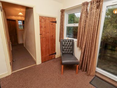 An entrance hall with a chair and window at Wayside Cottage in Newton-by-the-Sea