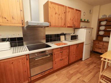 A kitchen with cabinets and appliances at Wayside Cottage in Newton-by-the-Sea