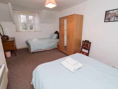 A bedroom with two beds and a wardrobe at Wayside Cottage in Newton-by-the-Sea