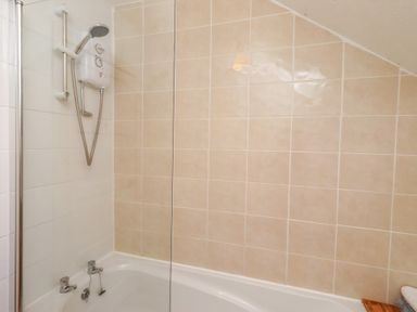 A bathroom with a bathtub and showerhead at Wayside Cottage in Newton-by-the-Sea