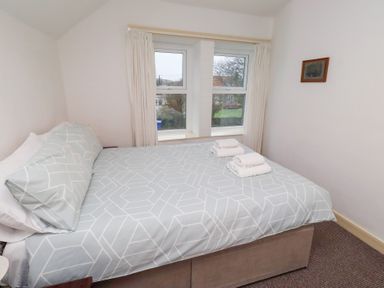 A bedroom with a bed and window at Wayside Cottage in Newton-by-the-Sea