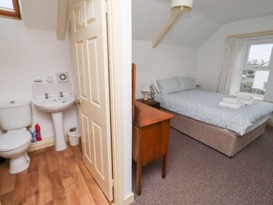 A bedroom with a bed and ensuite bathroom at Wayside Cottage in Newton-by-the-Sea