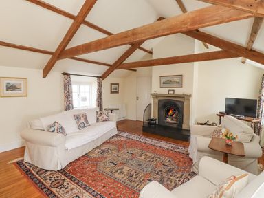 A living room with wooden beams a fireplace sofas a patterned rug and a television at Wynding Down in Bamburgh