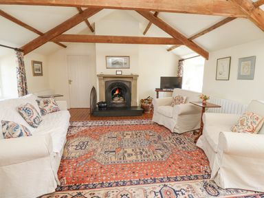 A living room with a fireplace two armchairs a sofa a television and an orange patterned rug at Wynding Down in Bamburgh