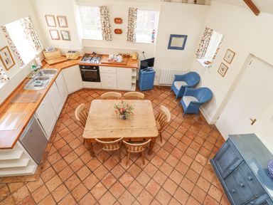 A kitchen with wooden table and chairs blue armchairs and wooden countertop at Wynding Down in Bamburgh