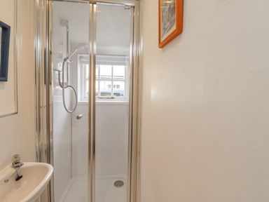 A bathroom with a shower enclosure sink and a window at Wynding Down in Bamburgh