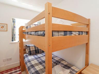 A bedroom with wooden bunk beds and plaid bedding at Wynding Down in Bamburgh