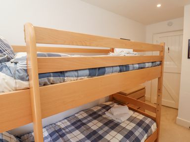 A bedroom with wooden bunk beds and folded towels on the beds at Wynding Down in Bamburgh