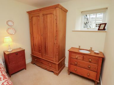 A bedroom with a wooden armoire and vanity at Wynding Down in Bamburgh