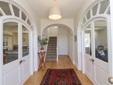 A hallway with wooden floor a rug and stairs at The Lookout Embleton