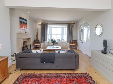 A living room with a gray sofa, a white sofa, a wooden coffee table, a fireplace, and large windows at The Lookout Embleton