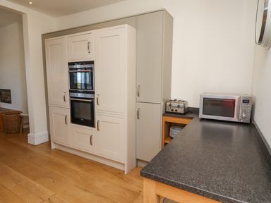 A kitchen with built in ovens a toaster a microwave and a black countertop at The Lookout in Embleton