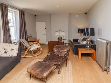A living room with leather chairs a rocking chair two sofas a side table with a lamp and a radiator at The Lookout Embleton