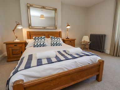 A bedroom with a wooden bed and two bedside tables with lamps at The Lookout Embleton