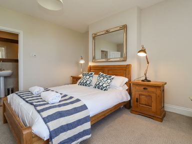 A bedroom with a wooden bed and bedside tables with lamps and a mirror on the wall at The Lookout Embleton