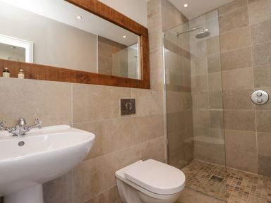 A bathroom with a white sink toilet and walkin shower with glass panel and tiled walls at The Lookout Embleton