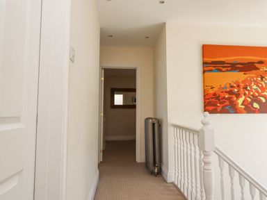 A hallway with a radiator and a colorful painting on the wall at The Lookout in Embleton