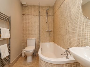 A bathroom with a bathtub shower toilet sink mirror and towel rack at The Lookout Embleton