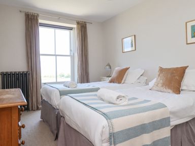 A bedroom with two single beds with striped throws and rolled towels at The Lookout (Embleton) in Embleton
