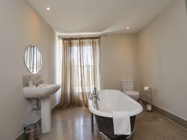 A bathroom with a bathtub sink toilet and a window with curtains at The Lookout Embleton
