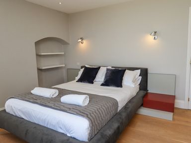 A bedroom with a double bed two black pillows two rolled towels and wall lamps at The Lookout Embleton