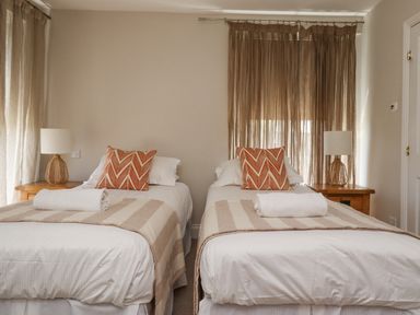 A bedroom with two single beds with striped throws and patterned pillows at The Lookout Embleton