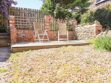 A garden area with two chairs on a wooden deck and a gravel ground at The Lookout Embleton