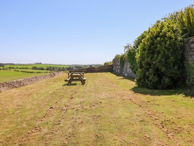A grassy outdoor area with picnic tables and stone walls at The Lookout (Embleton) in Embleton