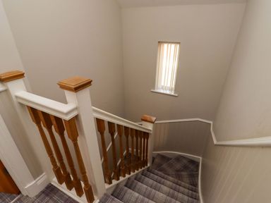 A staircase with wooden railing and window at Roe Deer in Lucker