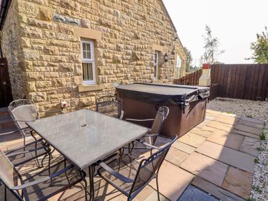 An outdoor area with a table and chairs next to a hot tub at Roe Deer in Lucker