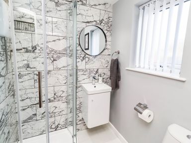 A bathroom with a shower, sink, and toilet at Flora Cottage in Beadnell