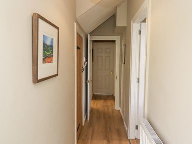 A hallway with wooden floor a radiator a framed picture and multiple doors at The Hollies in Bamburgh