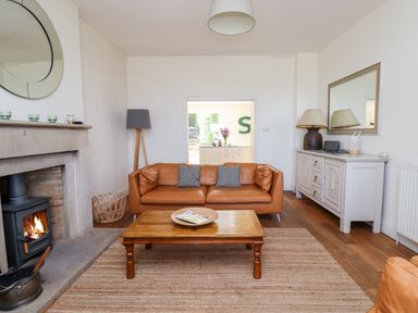 A living room with a brown leather sofa wooden coffee table fireplace and white cabinet at No6 Sea Lane in Embleton