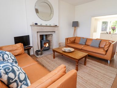 A living room with two leather sofas a wooden coffee table a fireplace with a wood stove and a TV at No6 Sea Lane in Embleton