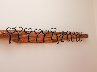A wooden coat rack mounted on a wall with black heart-shaped hooks at No6 Sea Lane in Embleton