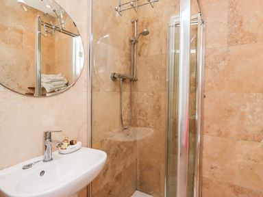 A bathroom with a sink mirror shower enclosure and toiletries at No6 Sea Lane in Embleton