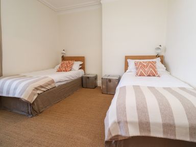 A bedroom with two single beds each with a striped blanket and patterned pillow at No6 Sea Lane in Embleton