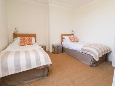 A bedroom with two single beds each with a striped blanket and orange pillow at No6 Sea Lane in Embleton