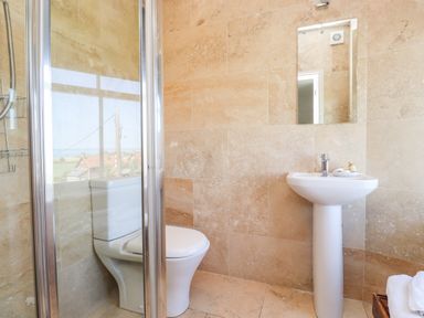 A bathroom with a shower enclosure toilet pedestal sink and mirror at No6 Sea Lane in Embleton