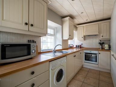 A kitchen with appliances cabinets a sink and tiled floor at The Arches in Bamburgh
