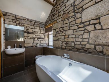 A bathroom with a bathtub sink toilet and stone walls at The Arches in Bamburgh