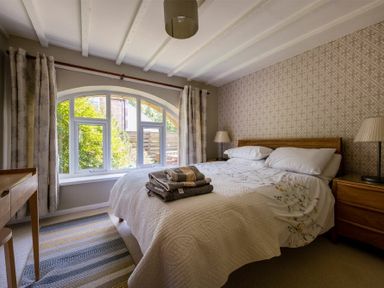 A bedroom with a double bed beside a large curved window at The Arches in Bamburgh