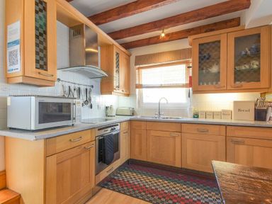 A kitchen with wooden cabinets a microwave an oven and a window at Farne Lookout in Seahouses