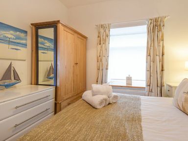 A bedroom with a bed covered with towels next to a wooden wardrobe and white drawers at Farne Lookout in Seahouses