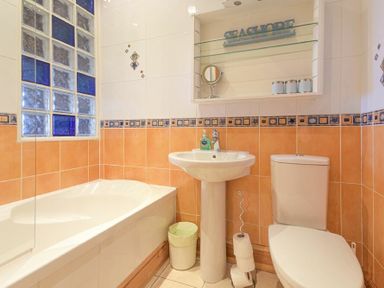 A bathroom with a bathtub sink and toilet with blue and white tiles at Farne Lookout in Seahouses
