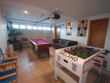 A game room with a foosball table a pool table a brown sofa and blue chairs at Farne Lookout in Seahouses