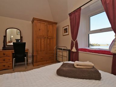 A bedroom with a wooden wardrobe dressing table and a window seat with a view at Turnstone Cottage Nr Bamburgh
