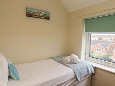 A bedroom with a single bed next to a window showing houses outside at Barnacle Cove Beadnell