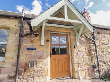 An entrance with a front door and stone wall at Rosefinch in Lucker